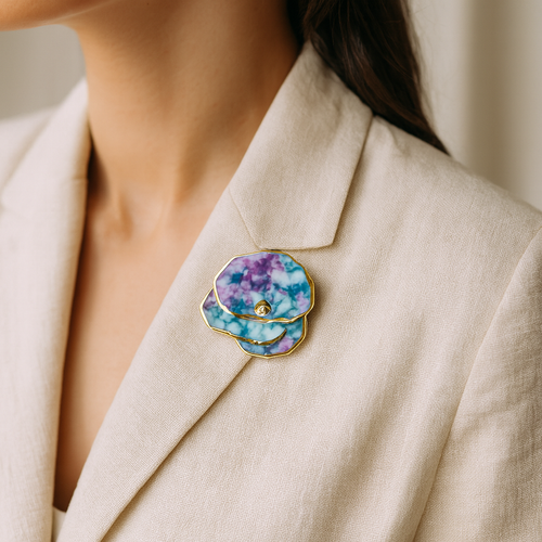 Close-up of a person wearing a beige blazer with a multicolored brooch with gold.