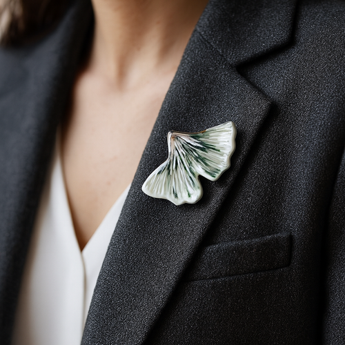 Person wearing a black blazer with a ginkgo-shaped brooch.