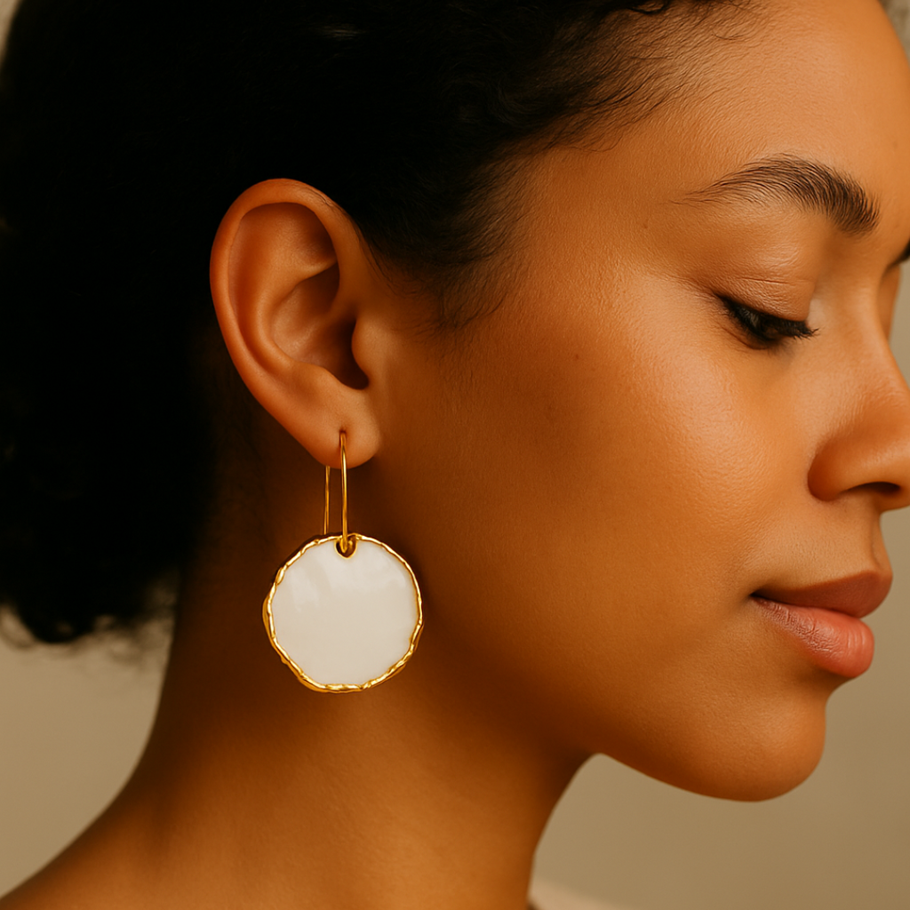 Close-up of a woman wearing a white and gold earring on a neutral background