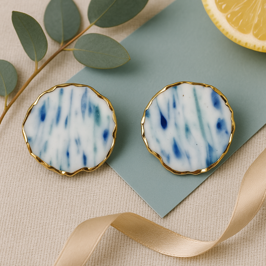 Pair of round earrings with a blue and white pattern on a textured surface.