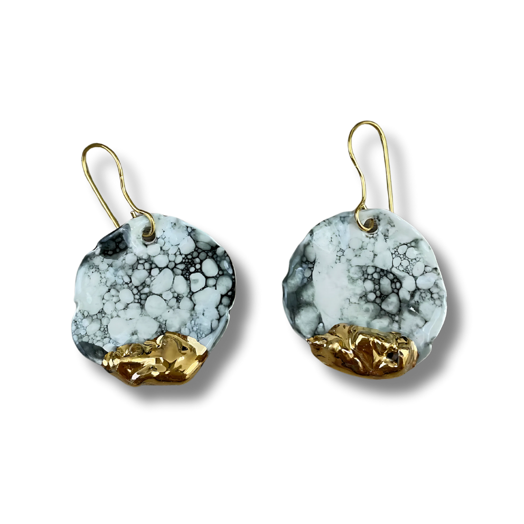 Pair of black and white earrings with gold accents on a white background