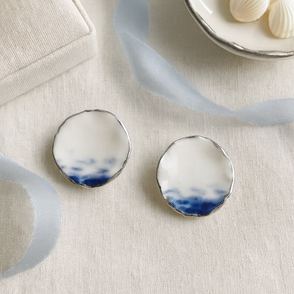 Pair of earrings with a blue and white design on a light fabric background