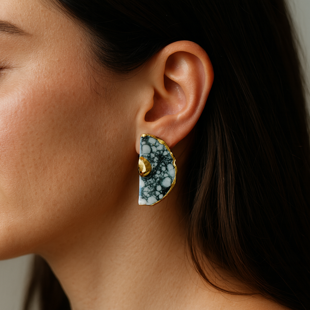 Close-up of a person wearing a pair of black and white earrings with gold accents.