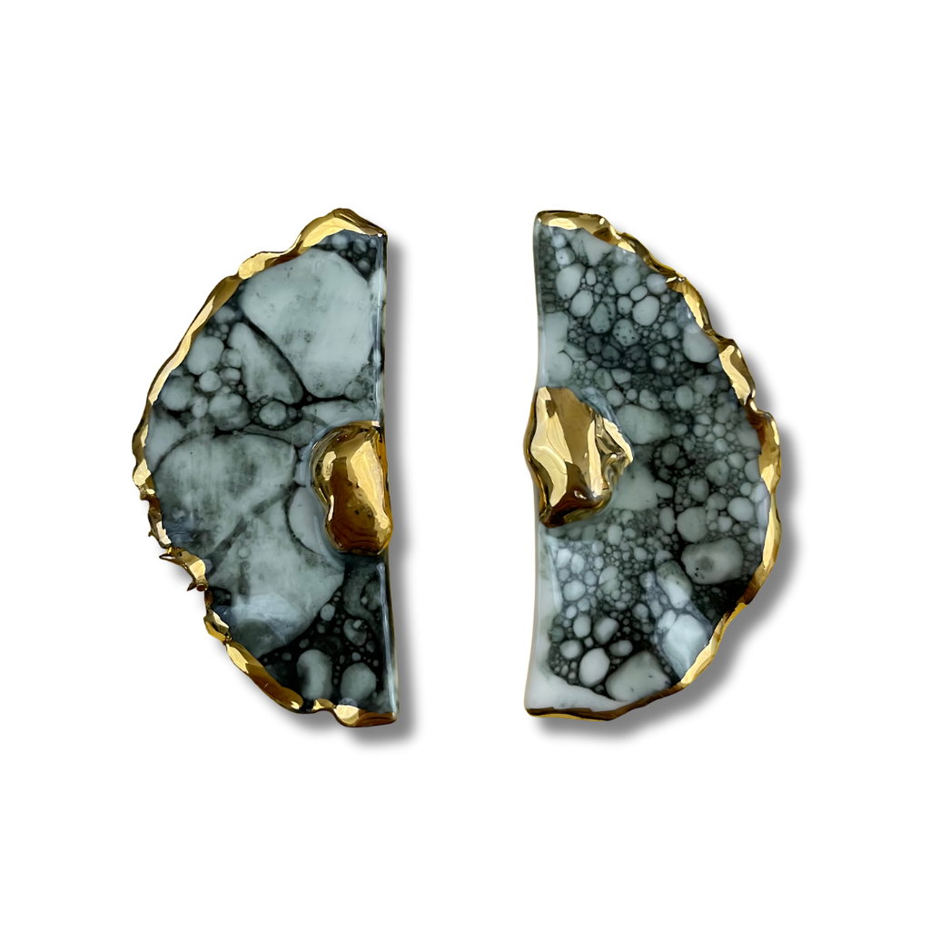 Pair of black and white earrings with gold accents on a white background