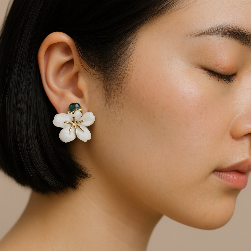Close-up of a woman wearing a pair of floral earrings with gold accents.