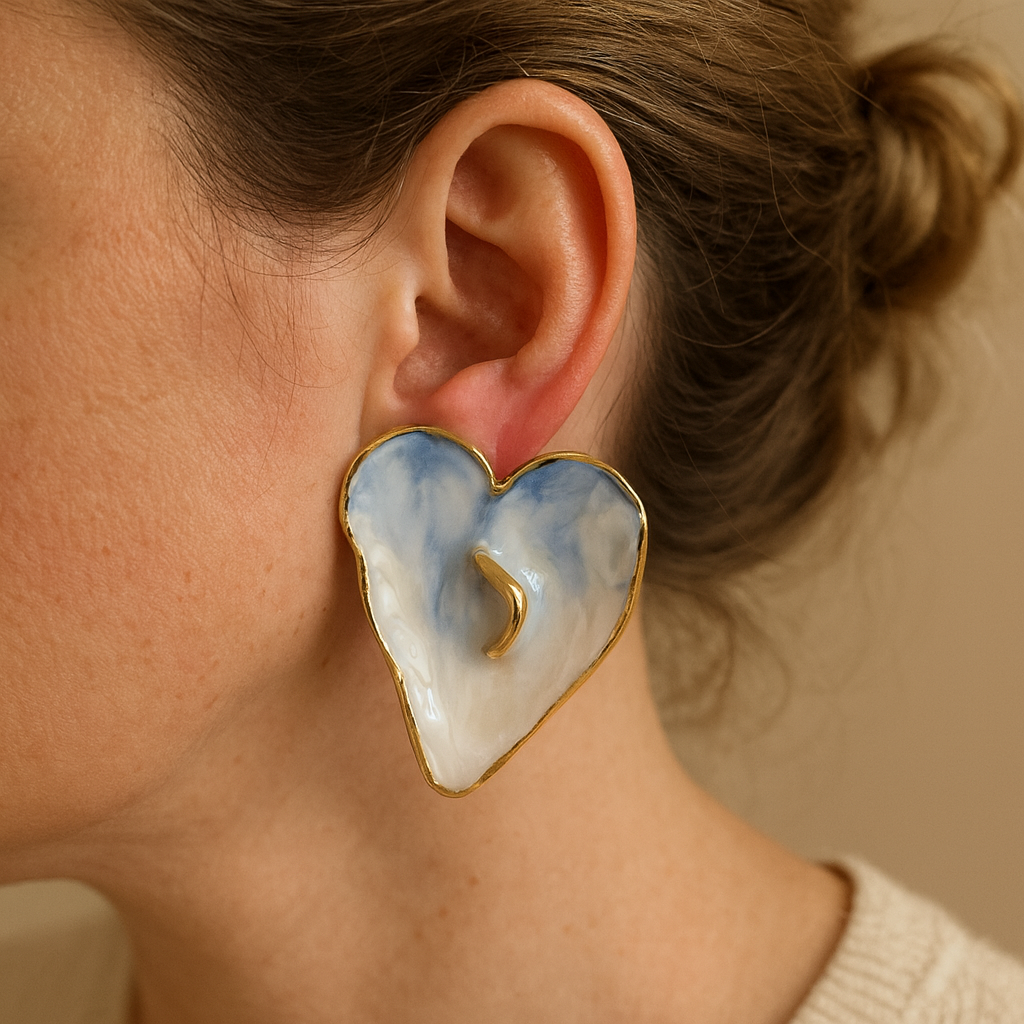 Heart-shaped earrings with gold details worn by a person